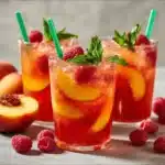 A refreshing glass of Raspberry Peach Lemonade with fresh fruit garnishes.