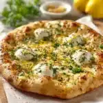 Delicious slice of Lemon Pizza topped with fresh herbs and lemon zest.