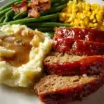 Classic meatloaf dinner with mashed potatoes, green beans, and corn on a plate