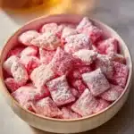 Bowl of Strawberry Shortcake Puppy Chow dessert with strawberries and cereal.