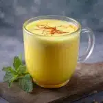 A delicious saffron latte served in a beautiful cup with a sprinkle of saffron on top.