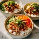 Delicious sticky chicken rice bowls with vibrant vegetables and sauce.