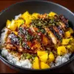 Delicious mango glazed chicken twists garnished with fresh herbs.