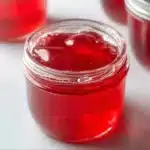 Jars of homemade rhubarb vanilla bean jelly on a wooden table