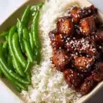 High protein sesame chicken dish garnished with sesame seeds and herbs