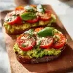 Avocado toast with fresh tomatoes and basil on a wooden table