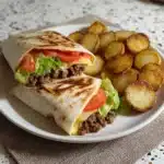 Beef wraps served with golden potato rings on a plate