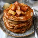 Macro-Friendly Apple Cinnamon Protein Pancakes topped with fresh apples and cinnamon.