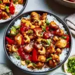 Plate of cashew chicken with vegetables and cashews, garnished for a tasty meal.