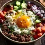 Delicious Greek Ground Beef Rice Bowl topped with fresh veggies and herbs.