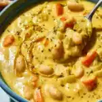 Bowl of creamy lemon white bean soup garnished with herbs and lemon slices